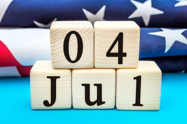 Tahta küplerin üzerinde 4 Temmuz tarihi ve mavi üzerine Amerikan bayrakları. Bağımsızlık Günü.