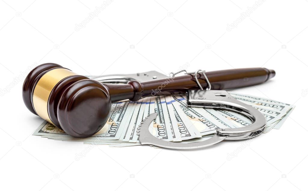 Judge's gavel with opened handcuffs and dollar bills on white.