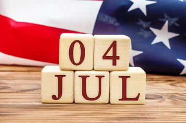 Tahta küplerde 4 Temmuz tarihi ve tahta arka planda Amerikan bayrağı. ABD 'nin bağımsızlık günü. 