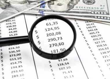 Finansal veriler ve para ile belgenin üzerine büyüteç.