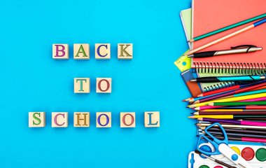 Mavi arka planda okul malzemeleri olan tahta küplerin 