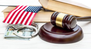 Hakim tokmağı, kelepçeler, kitaplar ve beyaz ahşap masada Amerikan bayrağı..