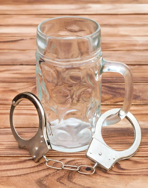 木製のテーブルの上にビールや手錠のための空のガラス アルコール依存症 — ストック写真