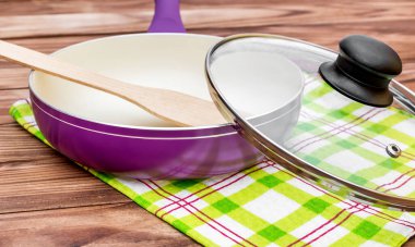 Mutfağın havlusunda tahta kürek ve cam kapaklı mor seramik kızartma tavası..