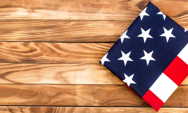 Folded american flag on wooden background. Space for text. Top view.