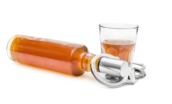 Şişe ve bardakta alkol ve kelepçe var. Alkol bağımlılığı kavramı.