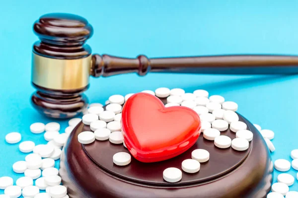 Kırmızı kalpli Gavel ve mavi haplı. Tıp Yasası.