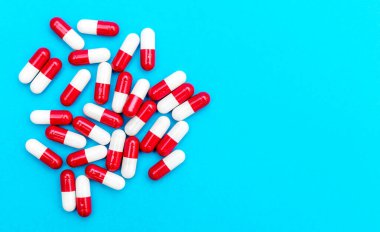 Mavi arka planda kırmızı-beyaz kapsüller yığını. Üst Manzara. Metin için boşluk. Tıbbi geçmiş.