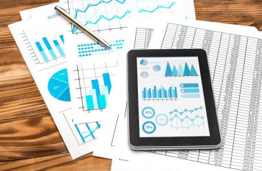 Finansal verileri olan belgelerde iş grafikleri bulunan tablet.