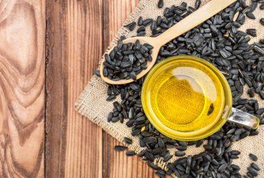 Cam bardakta pişmiş yağ ve çuval bezinde ayçiçeği tohumları olan ahşap kaşık. Üst görünüm.