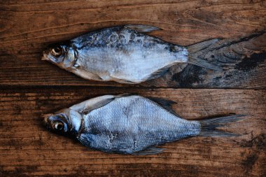 Koyu ahşap arka planda tuzlu, kuru nehir balığı. Pazarda kurutulmuş balık. Sokak yemeği..
