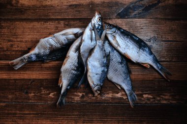 Koyu ahşap arka planda tuzlu, kuru nehir balığı. Pazarda kurutulmuş balık. Sokak yemeği..