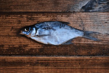 Koyu ahşap arka planda tuzlu, kuru nehir balığı. Pazarda kurutulmuş balık. Sokak yemeği..