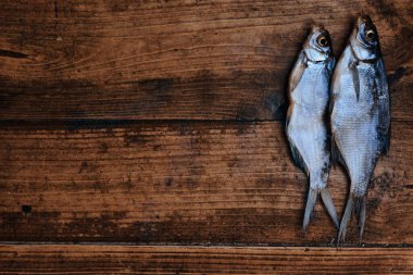 Koyu ahşap arka planda tuzlu, kuru nehir balığı. Pazarda kurutulmuş balık. Sokak yemeği..