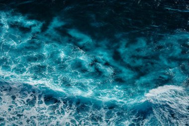 Okyanustaki su sıçrayan dalgaların hava görüntüsü. Mavi, temiz, dalgalı deniz suyu. Köpüklü sallanan dalgalar.