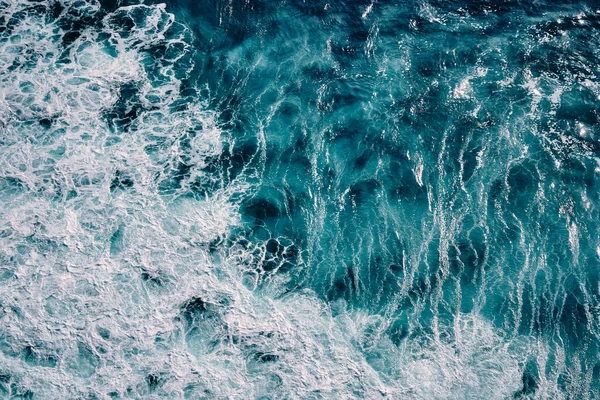 Okyanustaki su sıçrayan dalgaların hava görüntüsü. Mavi temiz dalgalı deniz suyu.