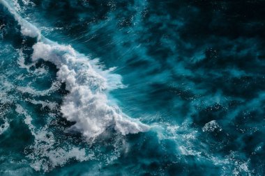Okyanustaki su sıçrayan dalgaların hava görüntüsü. Mavi temiz dalgalı deniz suyu.