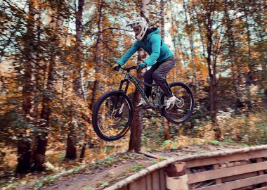 Rusya, Moskova - 2020 Sep: Genç adam ormanda MTB motoruyla atlıyor. Profesyonel yokuş aşağı sürüş. Doğada bisiklete binen biri. Bisikletli havalı bir sporcu. MTB bisikleti.