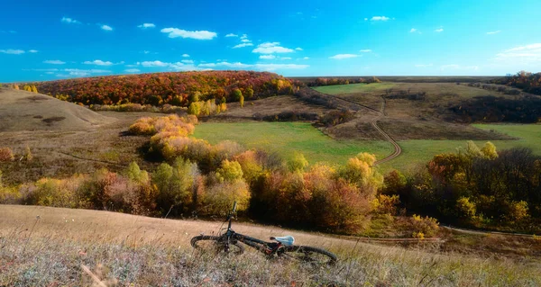 Aerial view of outdoor cycling. Mountain bike in wild nature landscape background. Autumn panoramic landscape of central Russia agricultural countryside with hills. High resolution file.
