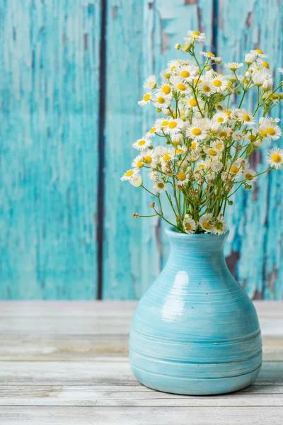Eski bir mavi vazoda beyaz çiçekler