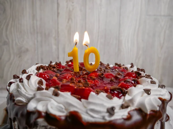 Number ten candle lit on top of a chocolate cherry cake — Stock Photo, Image
