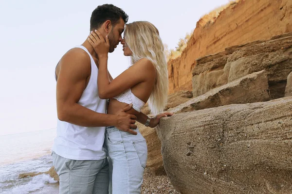 Hermosa pareja encantadora con pantalones vaqueros, posando en la playa de verano —  Fotos de Stock