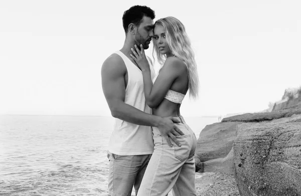 Hermosa pareja encantadora con pantalones vaqueros, posando en la playa de verano —  Fotos de Stock