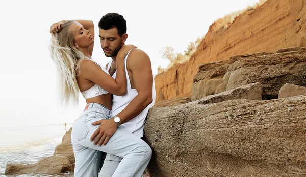 Hermosa pareja encantadora con pantalones vaqueros, posando en la playa de verano —  Fotos de Stock