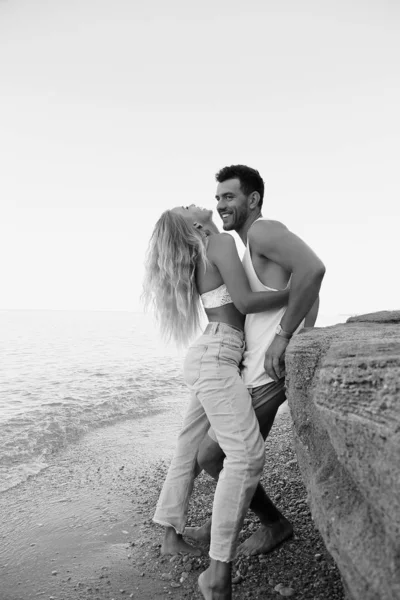 Hermosa pareja encantadora con pantalones vaqueros, posando en la playa de verano — Foto de Stock