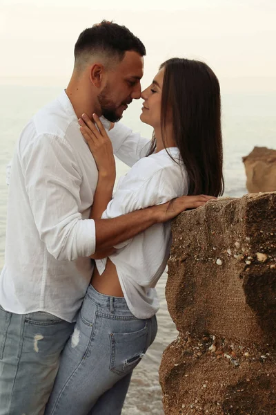 Hermosa pareja encantadora con pantalones vaqueros, posando en la playa de verano — Foto de Stock