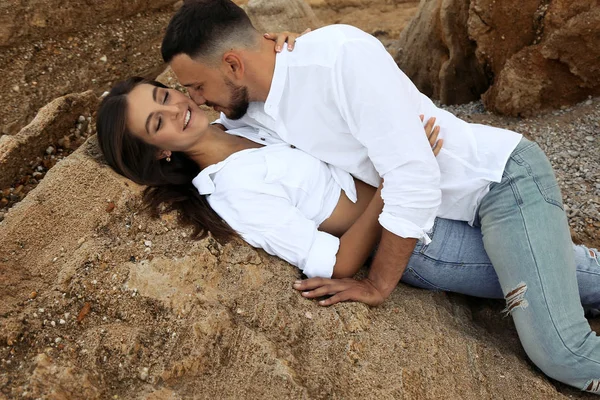 Hermosa pareja encantadora con pantalones vaqueros, posando en la playa de verano — Foto de Stock