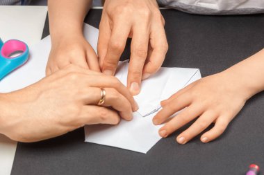 Bir şekil bir çocuk ve bir yetişkin ile birlikte beyaz kağıttan origami katlama işlemi. Yakın çekim. Ortak aile yaratıcılık, nesil nesil deneyim transferi kavramı