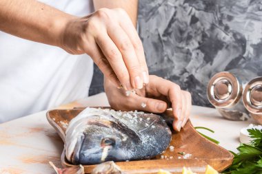 Dorado limon, zeytin yağı ve otlar ile balık pişirme işlemi. Eller yakın çekim. Ev yapımı gıda, mutfak hobi kavramı