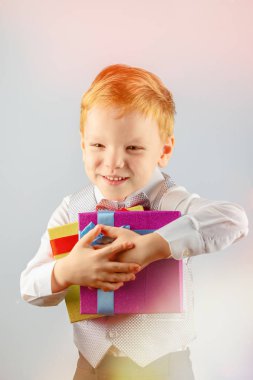 İki hediye onun elinde tutan ve gülümseyen beş yaşında mutlu kızıl saçlı bir çocuk