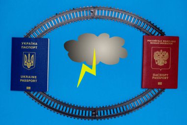 Ukrayna ve Rus pasaportları, kağıt bulutlar ve yıldırım raylar. Ukrayna ve Rusya arasındaki demiryolu iletişim iptali tehdidi kavramı. Uzay kopyalayın. Düz yatıyordu