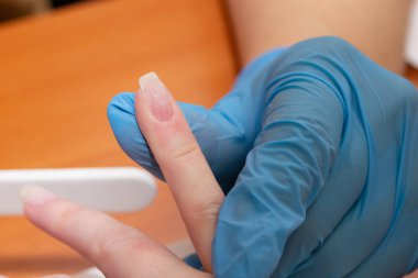 İşlem manikür. Sanatçı kolları çivi bir tırnak törpüsü ile yakın çekim