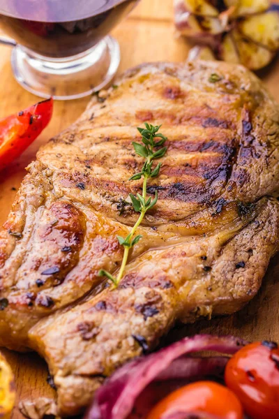 Сочный свиной стейк с веточкой свежего тимьяна, лимона и жареных овощей крупным планом — стоковое фото