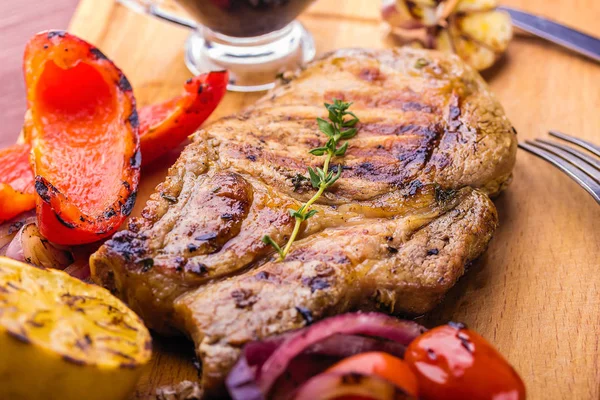 Carne de cerdo jugosa con una ramita de tomillo fresco, limón y verduras a la parrilla de cerca — Foto de Stock