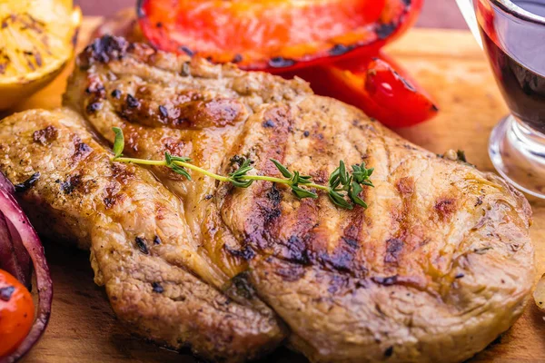 Carne de cerdo jugosa con una ramita de tomillo fresco, limón y verduras a la parrilla de cerca — Foto de Stock