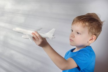 Altı yaşındaki bir çocuk bir yolcu uçağının oyuncak modeliyle oynuyor. Seyahat rüya konsepti