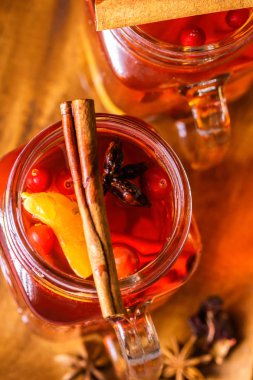 Ahşap bir tepsi üzerinde kızılcık, mandalina, Yıldız anason ve tarçın ile sıcak meyve çayı ile kokteyl kavanozları