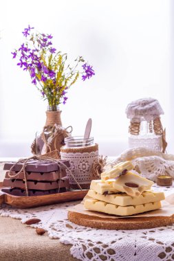 Karanlık, sütlü ve beyaz çikolata, yemekler ve pencere karşı yaban çiçekleri buket ile hala hayat. Boşluk Kopyala