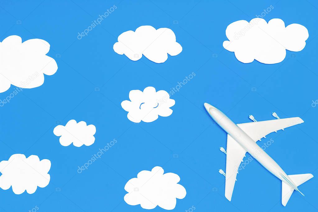 Flying through the clouds. Dreams of traveling, overcoming and success concept. Model passenger airplane and paper clouds. Flat lay