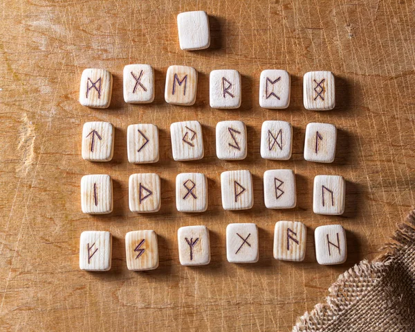 Anglo-saxon wooden handmade runes on the vintage table On each rune symbol for fortune telling is designated
