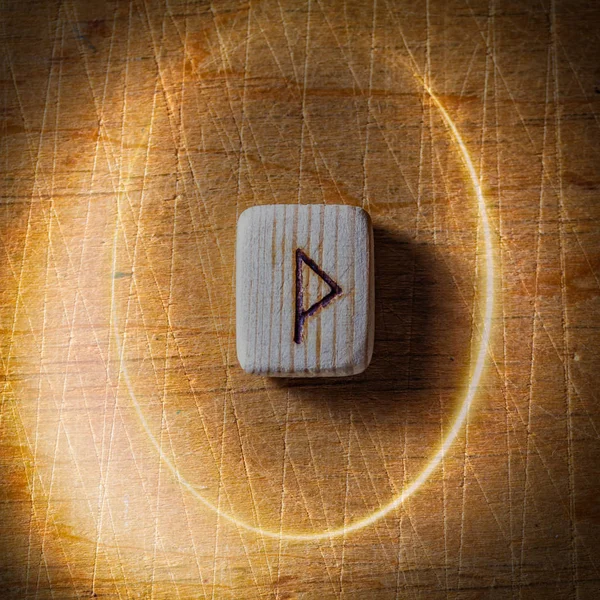 Wunjo. Handmade scandinavian wooden runes on a wooden vintage background in a circle of light. Concept of fortune telling and prediction of the future