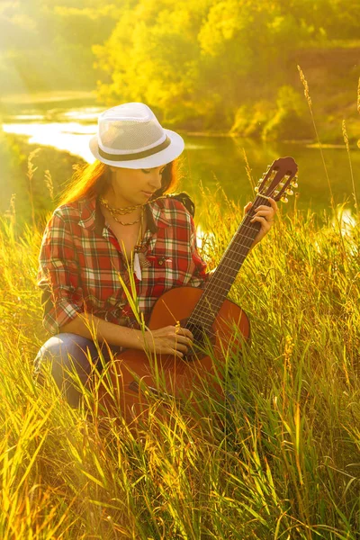 Hermosa, mujer feliz en el verano en los rayos de la puesta de sol con una guitarra. Concepto de libertad creativa, diversión y vacaciones de verano —  Fotos de Stock