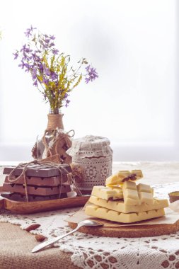 Karanlık, sütlü ve beyaz çikolata, yemekler ve pencere karşı yaban çiçekleri buket ile hala hayat. Boşluk Kopyala