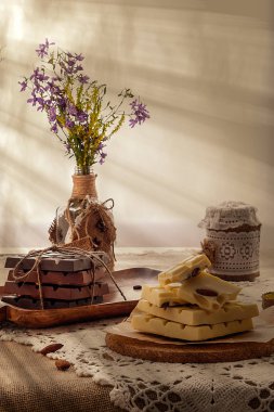 Karanlık, sütlü ve beyaz çikolata, yemekler ve pencere karşı yaban çiçekleri buket ile hala hayat. Boşluk Kopyala