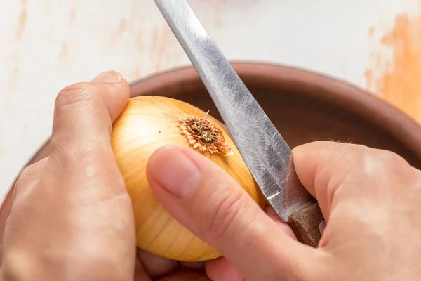 O cozinheiro limpa cebolas com um close-up de faca. Conceito de culinária orgânica — Fotografia de Stock