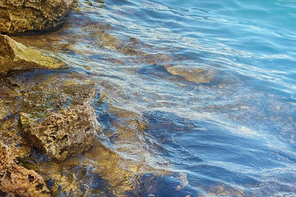 Piedra cerca del río. Las olas corren en la costa. Puesta de sol de verano. Los rayos del sol se reflejan en el agua —  Fotos de Stock